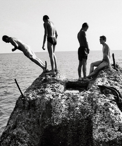 four-young-teen-boys-in-different-stages-of-jumping-off-a-rock