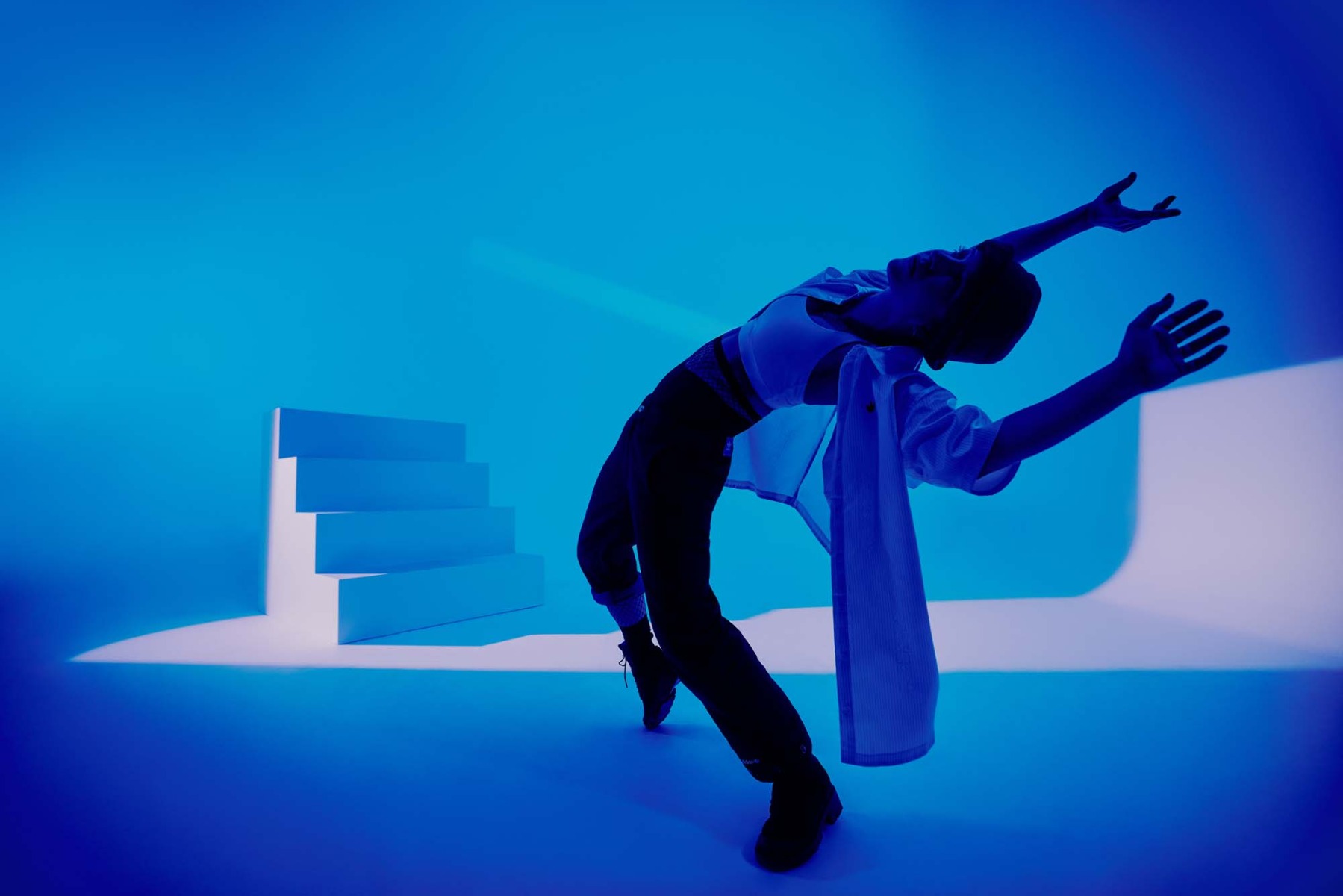 blue-lit-dancer-in-studio-back-bend-stair-set-in-background