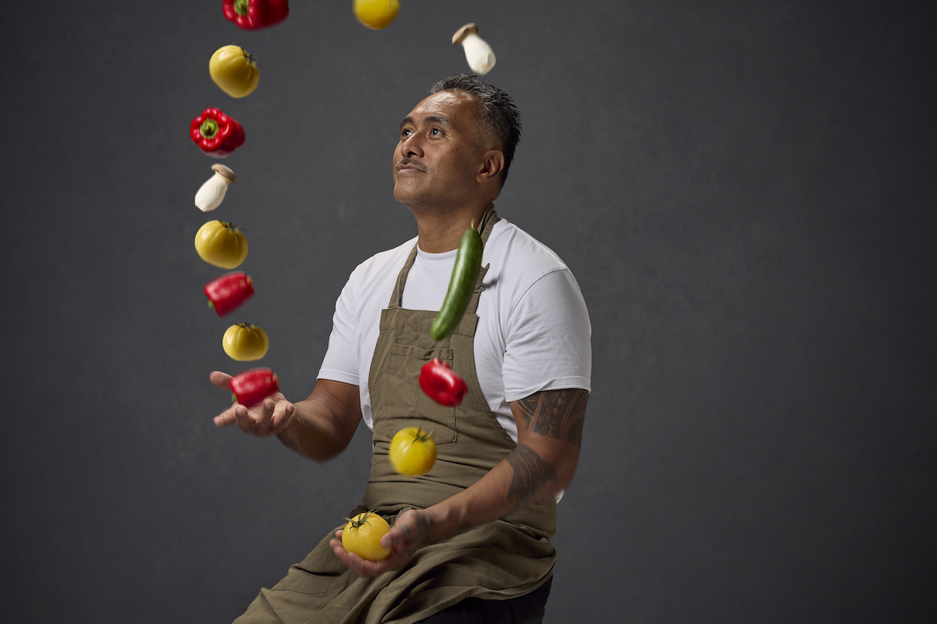 Tony juggling vegetables against a dark grey backdrop