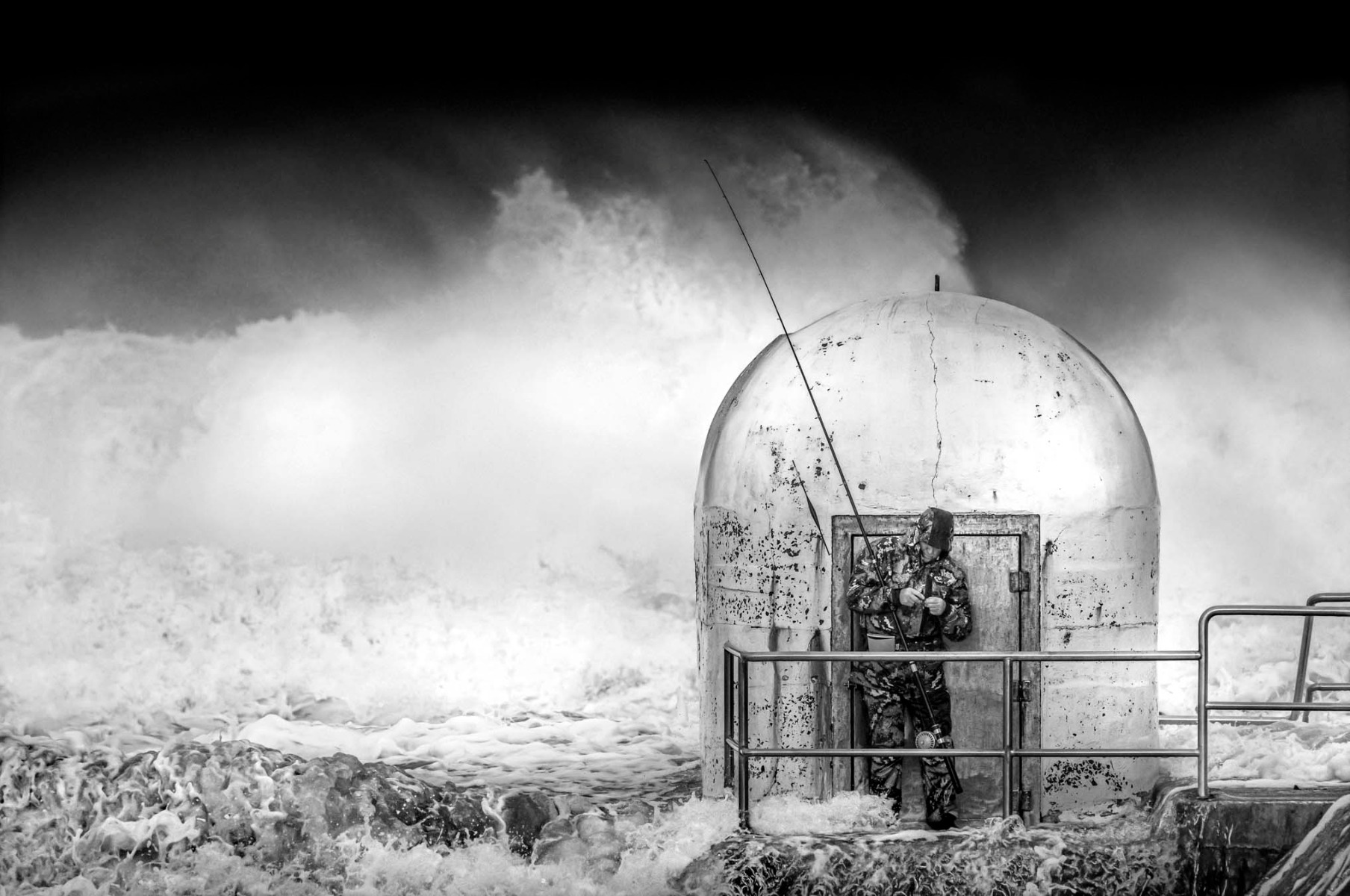 black-and-white-photograph-of-man-fishing-admist-turbluent-ocean