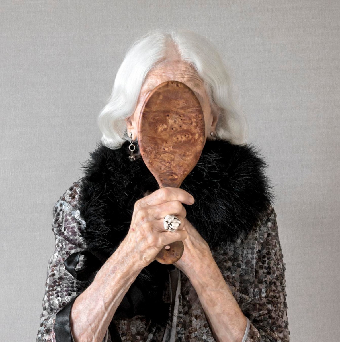 elderly-woman-holds-ornate-mirror-over-her-face