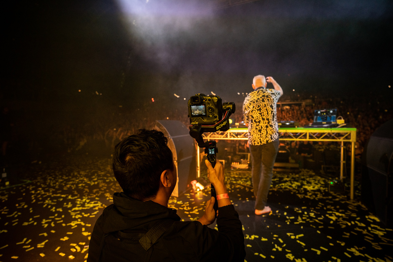 Brian Purnell filiming Fatboy Slim from behind as he performs on stage 