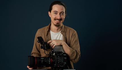 Jake Halfhyde holding a Canon EOS C500 Mark II camera against a dark background