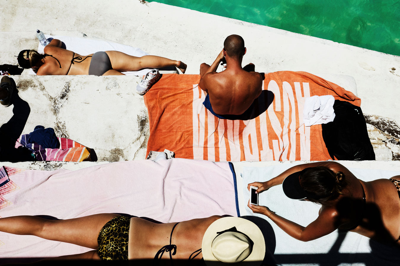 arial-shot-of-bright-high-contrast-scene-humans-sunbaking-reading-on-phones