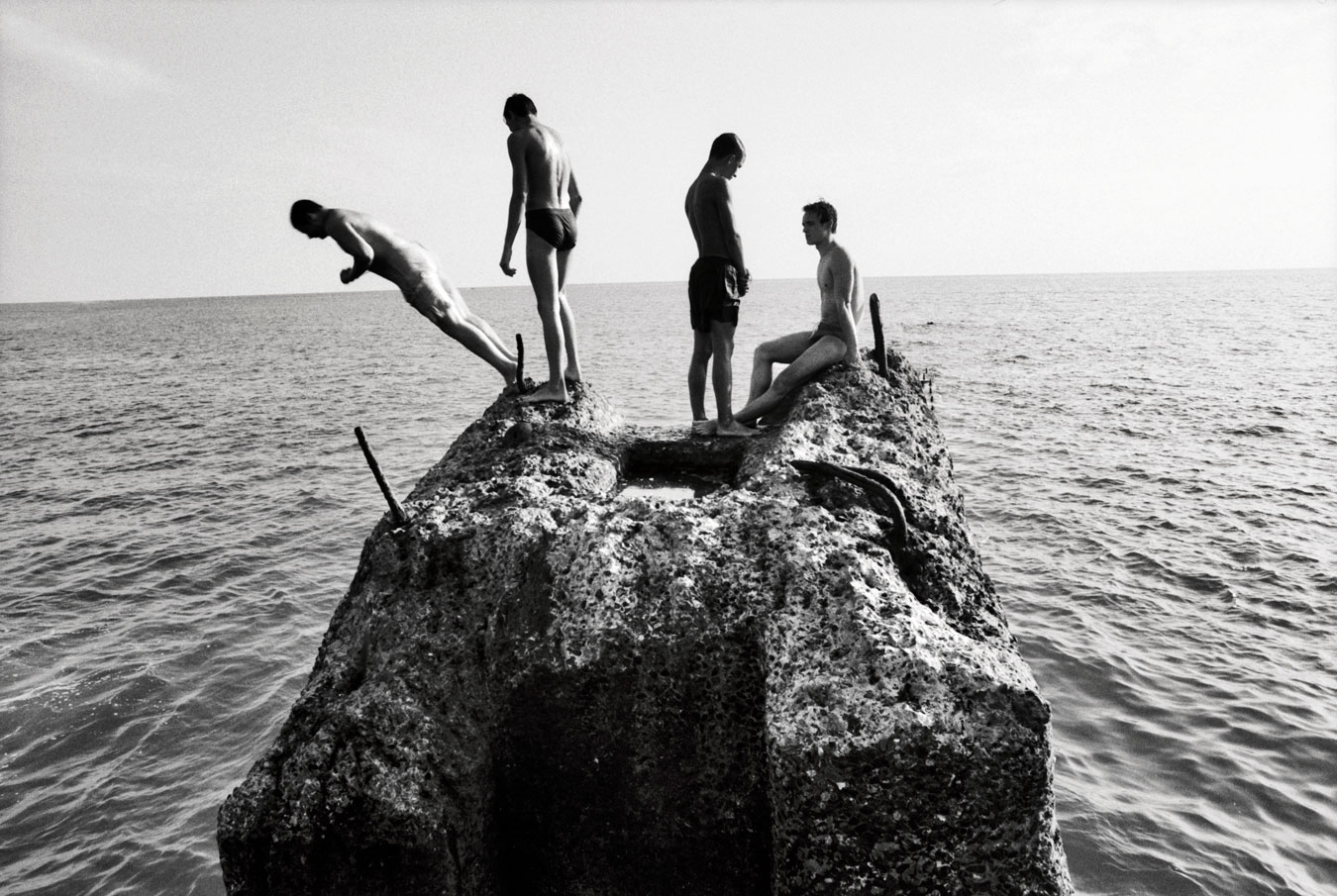 four-young-teen-boys-in-different-stages-of-jumping-off-a-rock