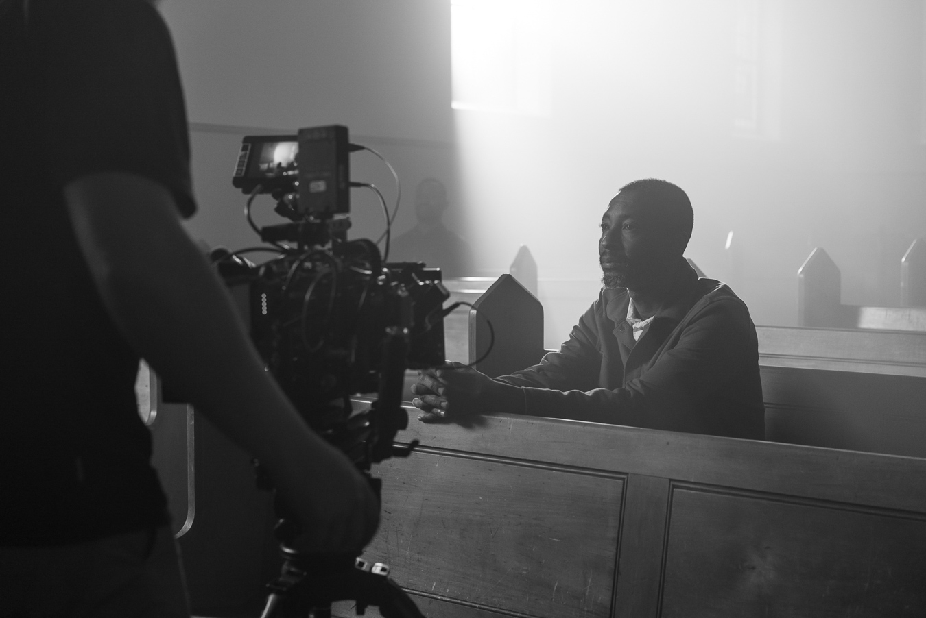 man-sitting-in-church-pew-being-filmed-with-large-cinema-camera