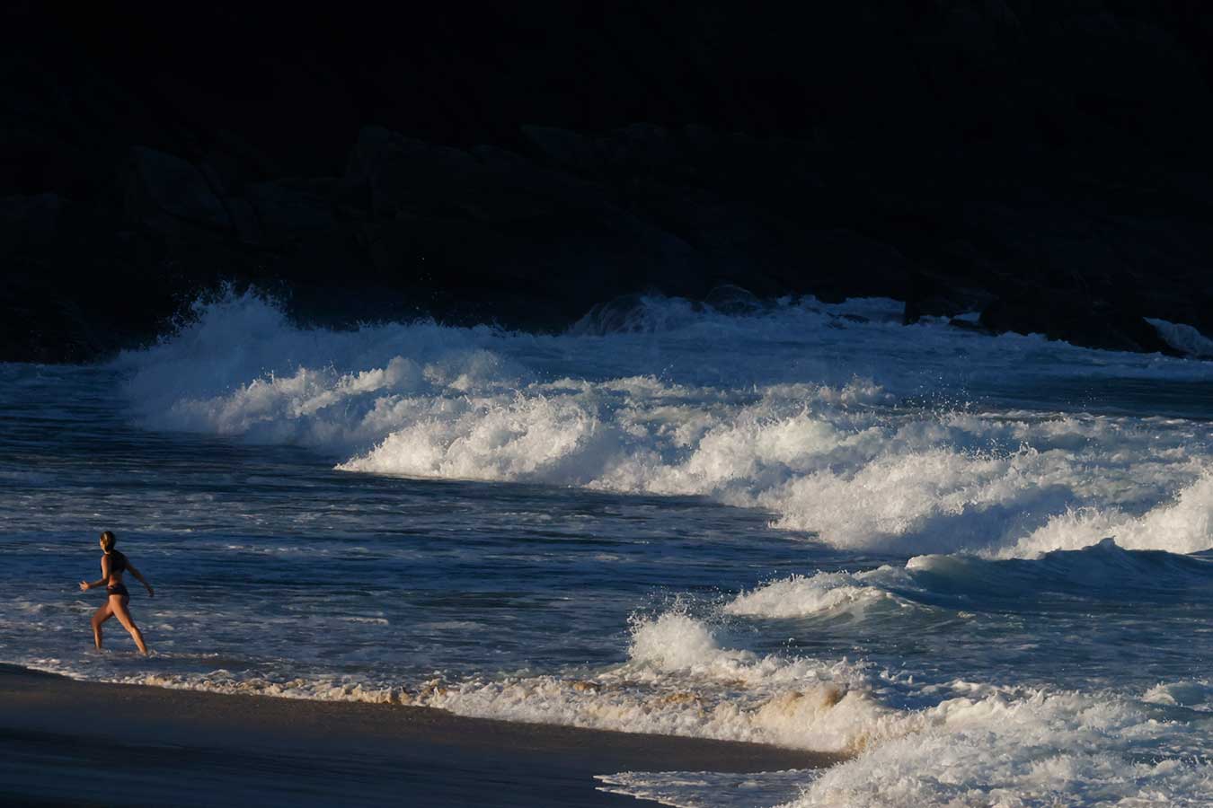 woman-exiting-surf-among-encroaching-afternoon-shadows