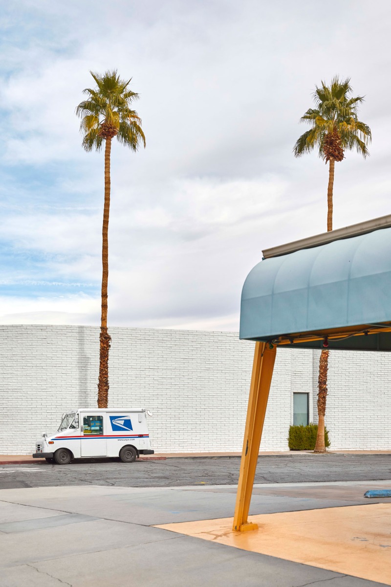 usps-van-parked-in-bright-urban-landscape-near-a-palm-tree