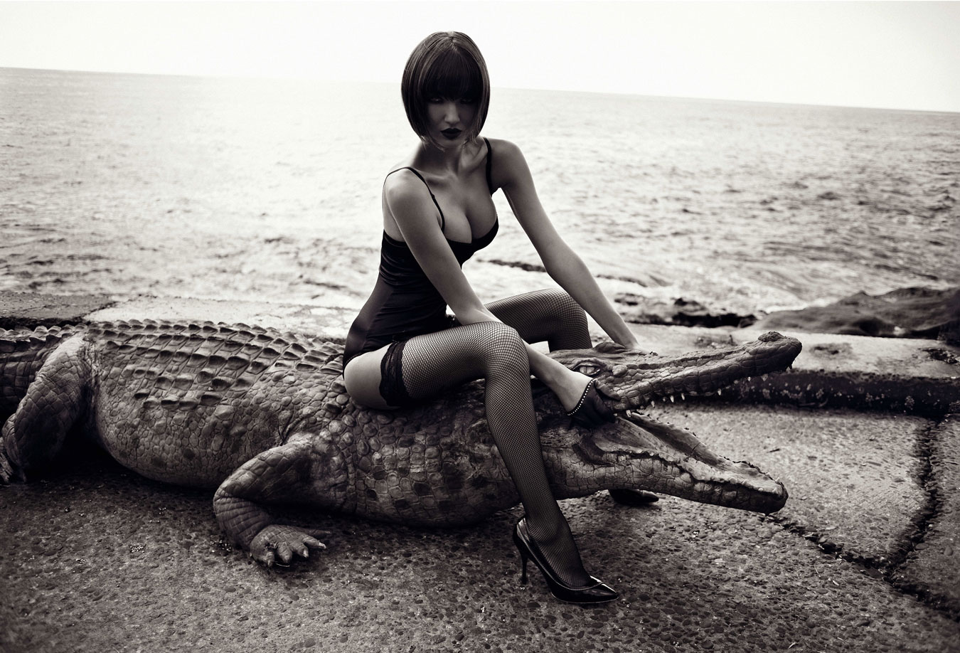 black-and-white-photograph-of-woman-with-bob-haircut-and-fishnets-sitting-on-fake-crocodile
