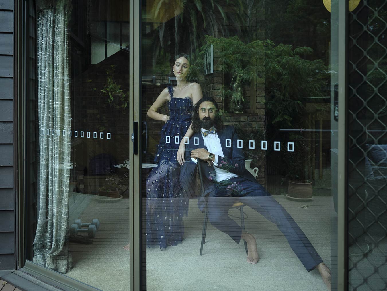 man-andwoman-behind-glass-door-dressed-formally-in-domestic-setting-without-shoes