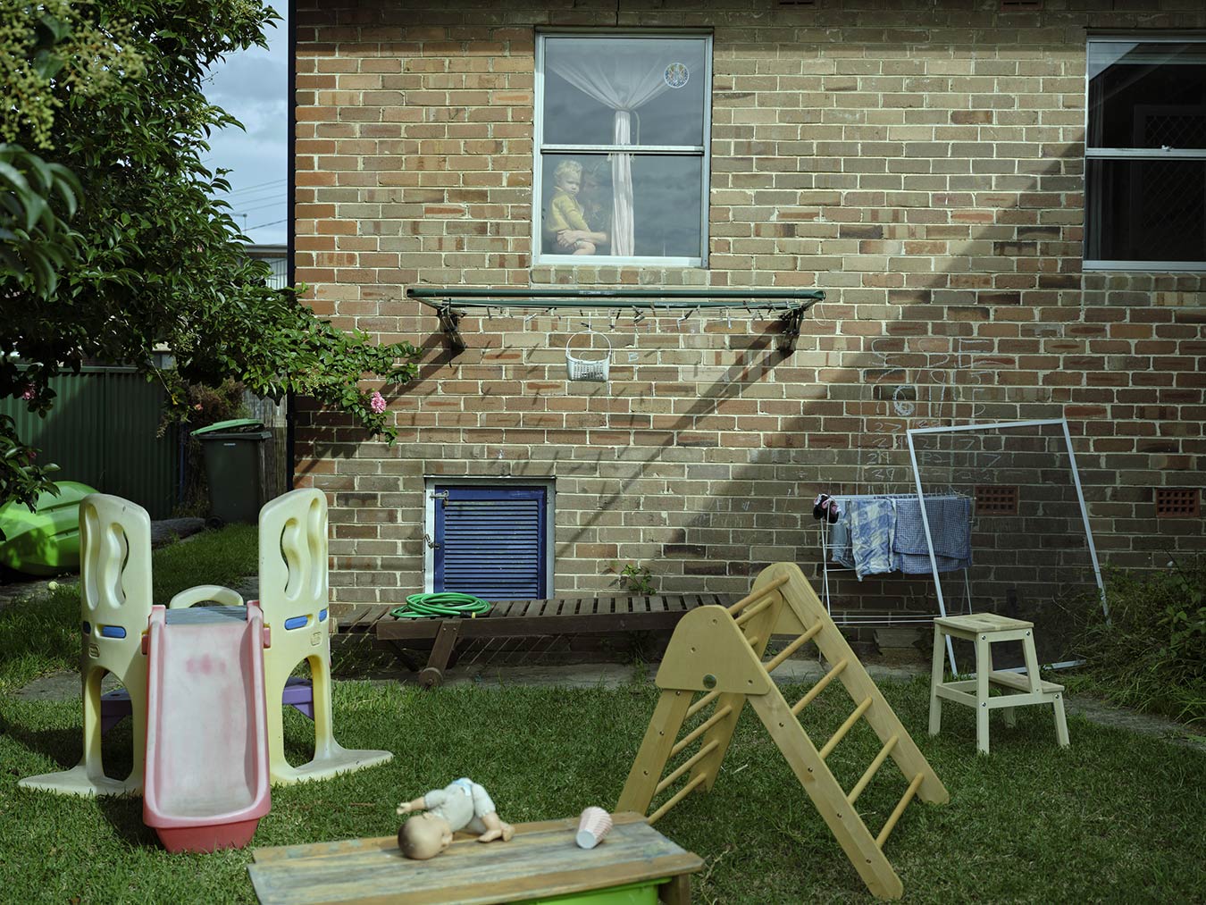 backyard-with-scattered-toys-woman-and-child-in-window