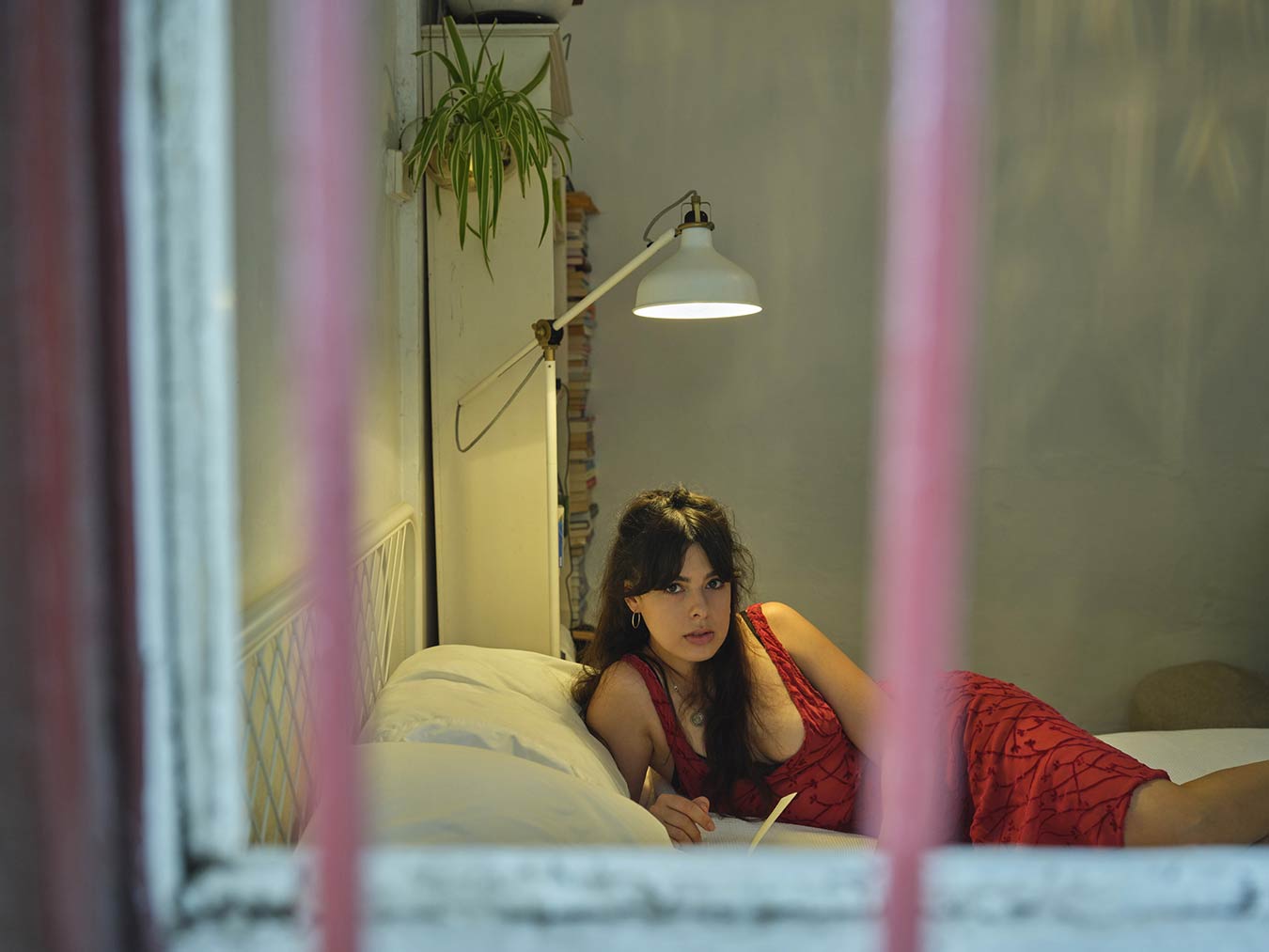 portrait-of-woman-in-red-dress-lying-on-bed-through-a-window