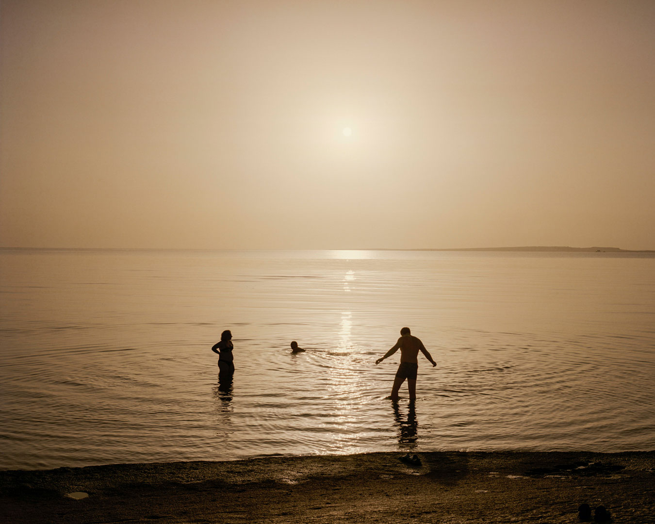 a-family-at-sunrise-bathing-in-the-water-in-sillouette-flooded-in-golden-light