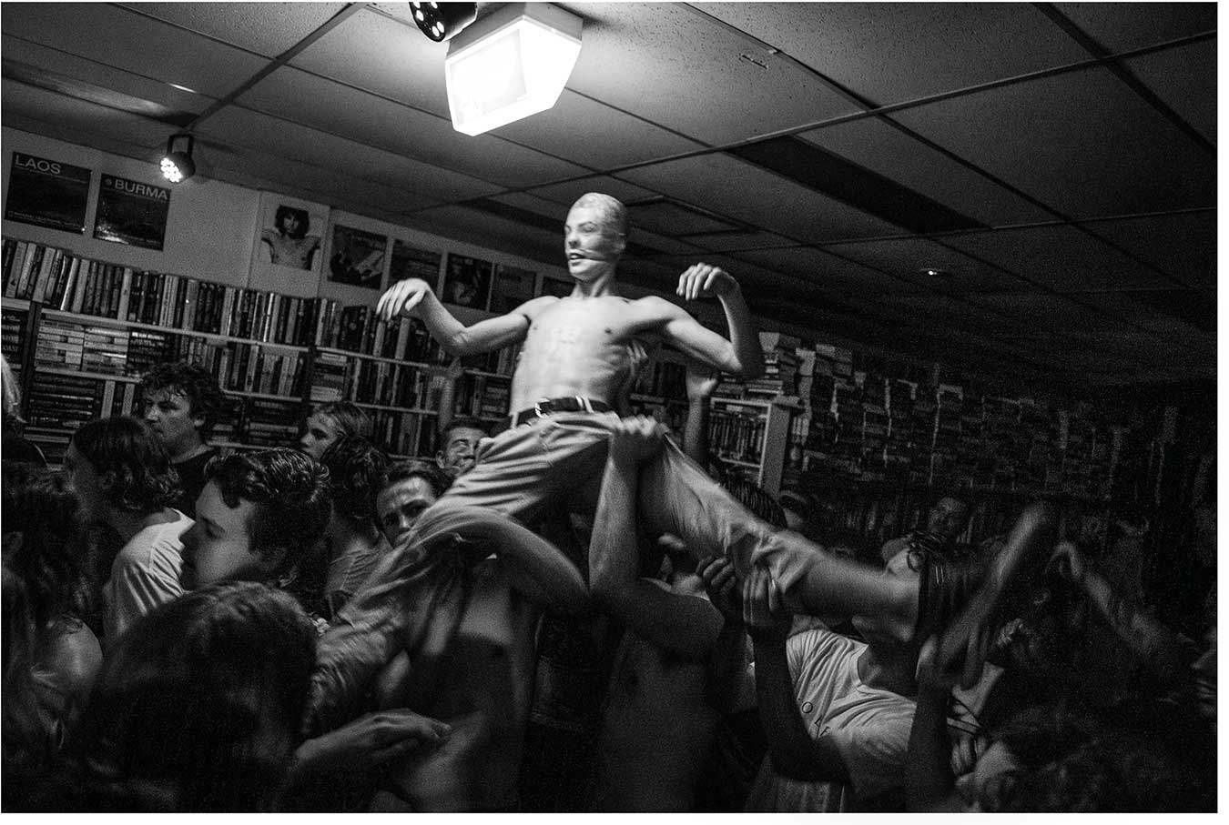 black-and-white-photo-of-a-man-with-a-stocking-pulled-over-his-head-at-a-music-performance-in-a-bookstore