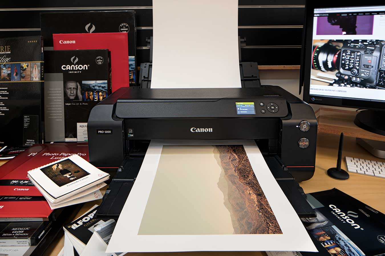 a-canon-pro-1000-printer-mid-print-of-a-landscape-surrounded-by-paper-and-inks