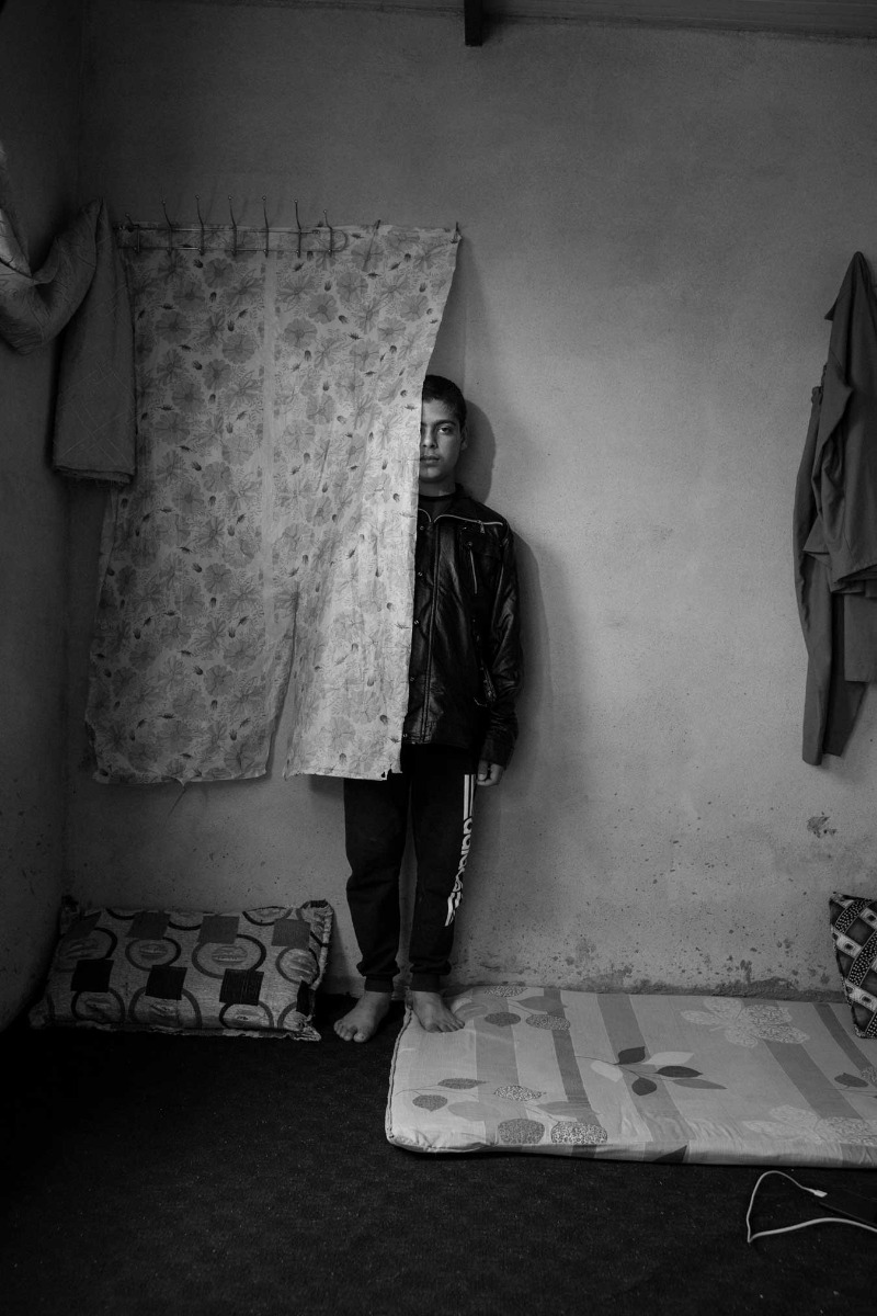 black-and-white-image-f-boy-partially-obscured-behind-wall-hanging