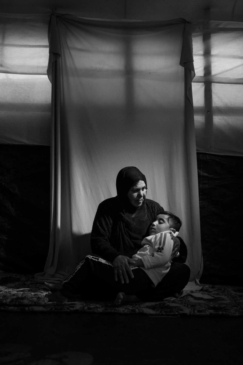 black-and-white-portrait-of-woman-cradelling-grandson-white-a-white-sheet-strung-up-behind-them