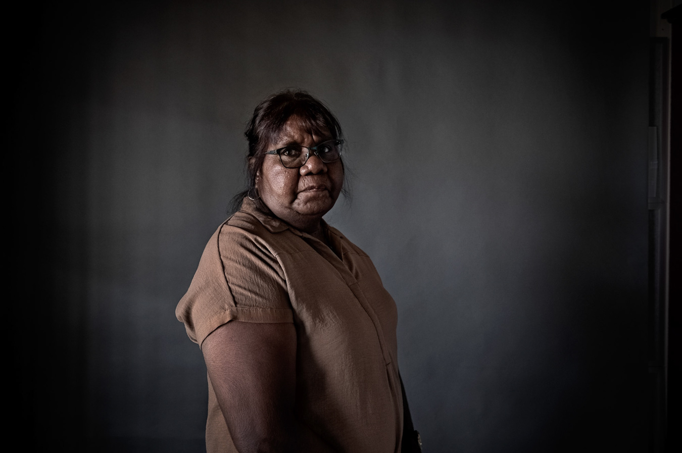 indigenous-australian-woman-in-brwn-shirt-standing-eyes-to-camera