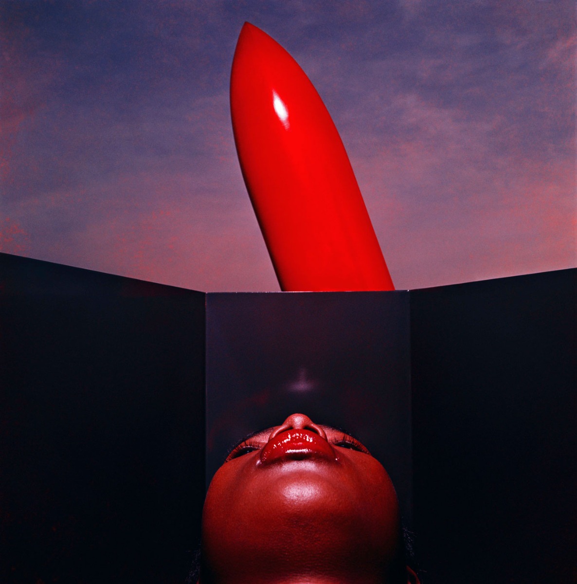 womans-upturned-face-looks-toward-giant-phallic-red-lipstick-in-background-against-purple-sky