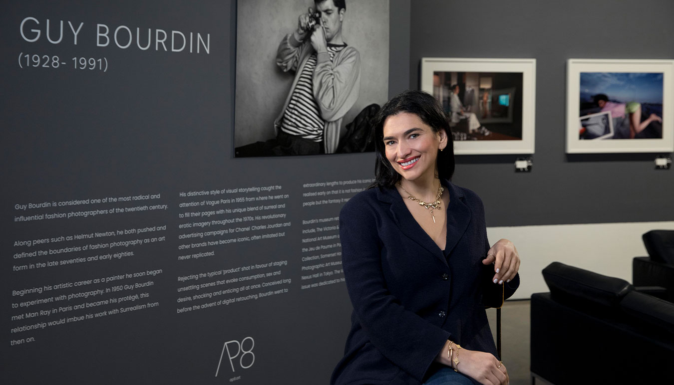 woman-seated-in-front-of-exhibition-signage-guy-bourdin-prints-in-background