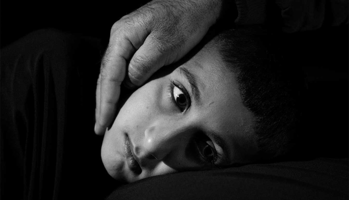 black-and-white-image-of-boy-with-reassuring-hand-over-his-cheek