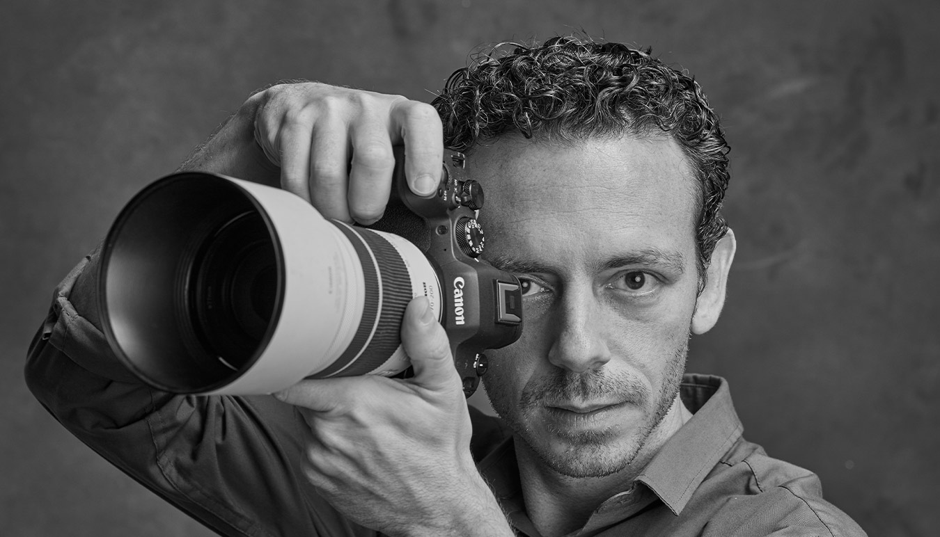 black-and-white-portrait-of-man-holding-canon-camera-to-his-eye